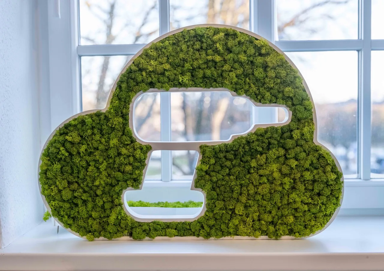 Eine Wolke aus Holz und Moos. In der Mitte der Wolke ist ein Akkuschrauber ausgeschnitzt.